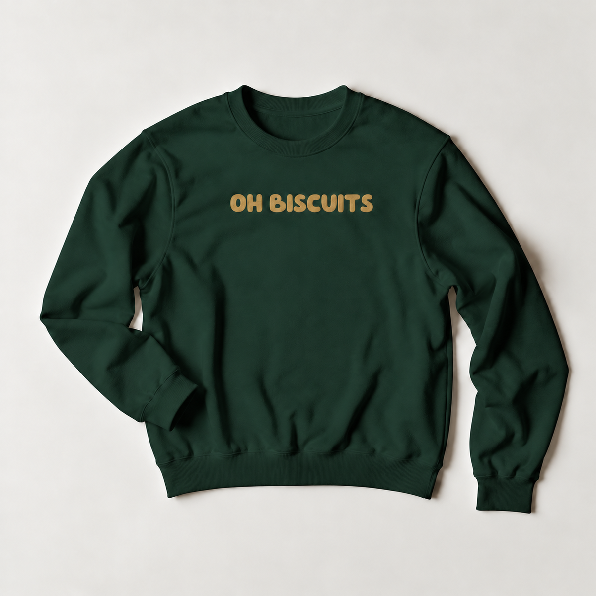 A dark green crewneck sweatshirt with the words 'OH BISCUITS' printed across the chest in a gold-colored retro font, laid flat on a light gray background.